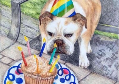 little bull dog standing in a chair. He wears a striped party hat and is looking at a birthday cake with candles on a polka dot paper plate