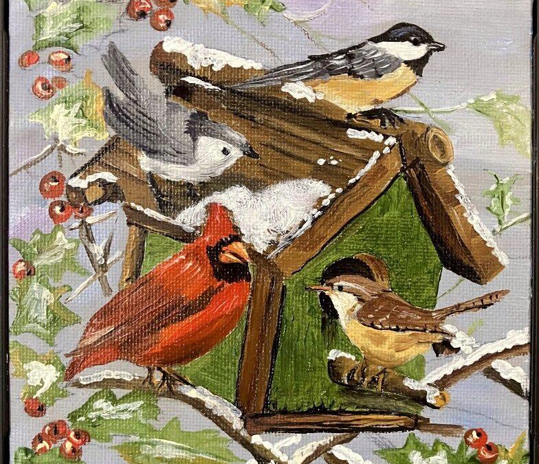 painting of 4 colorful birds on a bird house on a holly bush covered in snow
