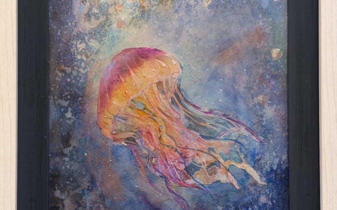 Water color painting of a jelly fish in the ocean. The entire image is multicolor with blues and purples in the water and shades of reds and yellows in the jelly fish